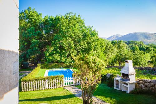 a backyard with a pool and a fence and a tree at Los Chendas in Villanueva de Ávila