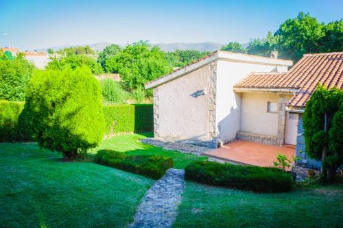 a garden with a small white building and a house at Los Chendas in Villanueva de Ávila
