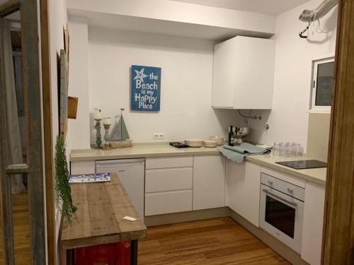 a kitchen with white cabinets and a blue sign on the wall at BEACH ATTIC in Zahara de los Atunes
