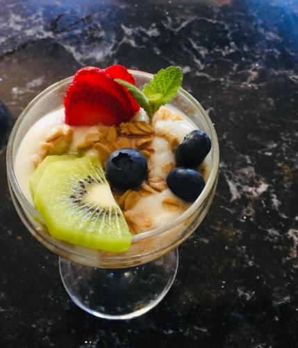 a bowl of yogurt with fruit and a strawberry at Beaconsfield Bed and Breakfast - Victoria in Victoria