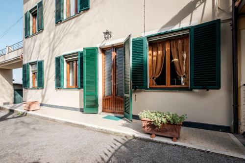 a house with green shutters and a potted plant at La terrazza del Bimbo in Fucecchio