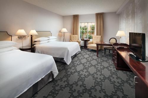 a hotel room with two beds and a flat screen tv at Anaheim Majestic Garden Hotel in Anaheim
