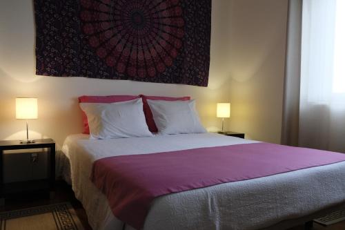 a bedroom with a bed with purple sheets and two lamps at Apartamento Tres Marias in Lagoa