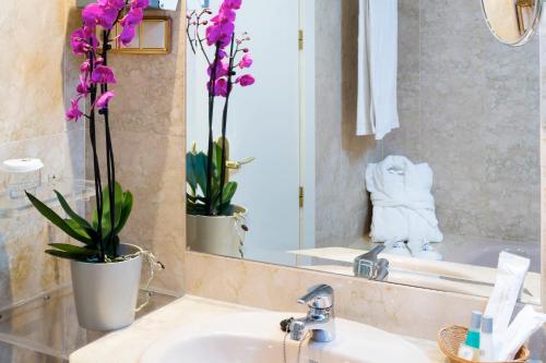 a bathroom with a sink and a mirror and flowers at VP Jardín de Tres Cantos in Tres Cantos