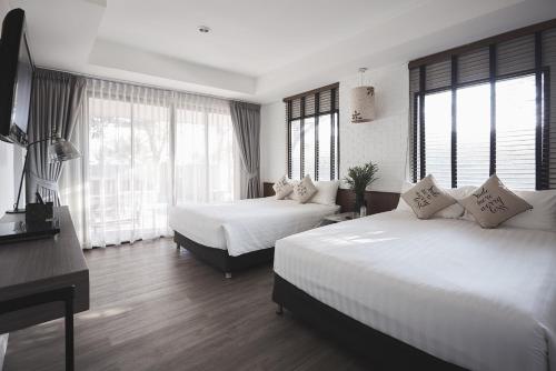 a bedroom with two beds and a desk and windows at Siambeach Resort in Cha Am