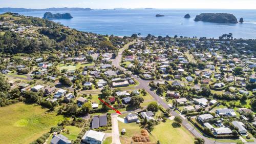 an aerial view of a suburb with houses and the ocean at Hahei Beach Bach. in Hahei