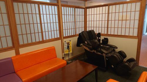 an orange couch and a table in a room withwindows at Hotel Oak Forest in Hakuba