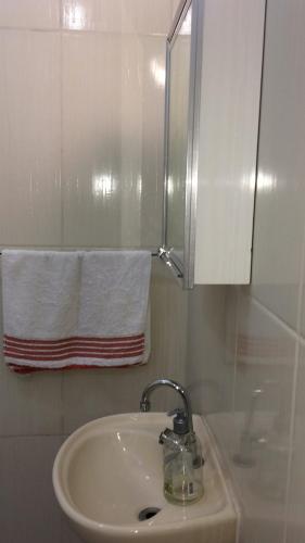 a bathroom with a sink and a mirror and a towel at Próximo ao Consulado - Quarto Inteiro in Porto Alegre