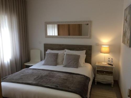 a bedroom with a large white bed with a night stand at Casinha do Rossio in Aveiro