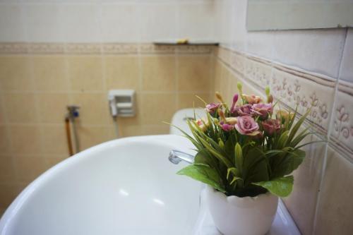 eine Vase mit Blumen auf einem WC im Bad in der Unterkunft Warisan Indah Homestay KLIA 2 Melayu sahaja in Sepang