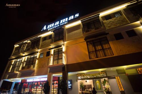 a building with a sign on top of it at night at Amamas Boutique Hotel Kuching in Kuching