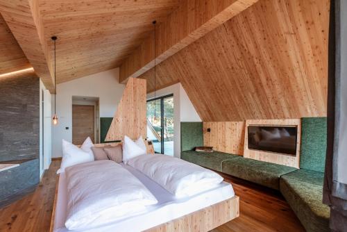 a large bed in a room with wooden ceilings at Oberhauser Hütte Rodenecker - Lüsner Alm in Luson