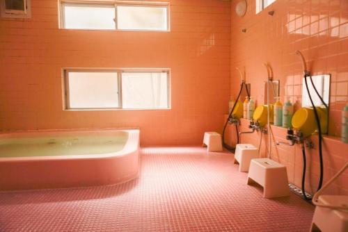 une grande salle de bains orange avec une baignoire et une fenêtre. dans l'établissement Karuizawa Pension Sato no Nukumori, à Karuizawa