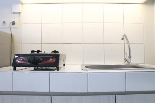una cocina con estufa y fregadero en Furnished Studio Apartment The Springlake Summarecon Bekasi By Travelio, en Bekasi