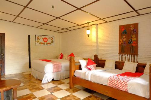 a room with two beds and a table at OYO 604 Cemara's Homestay in Batu