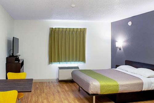 a hotel room with a bed and a table and a chair at Welcome Suites Springdale in Springdale