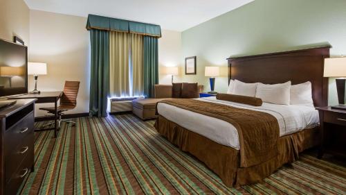Habitación de hotel con cama grande y escritorio. en Best Western Plus Chain of Lakes Inn & Suites en Leesburg