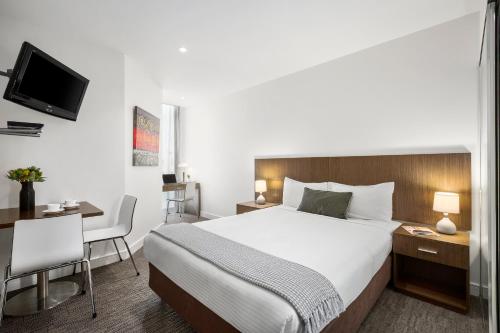 メルボルンにあるQuest Ivanhoeの大きなベッドとデスクが備わるホテルルームです。