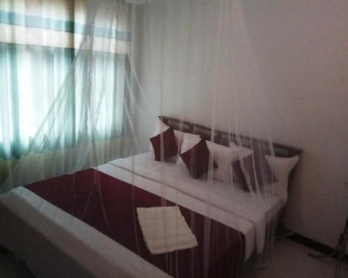 a bedroom with a bed with pillows and a window at RIO Homestay in Haputale