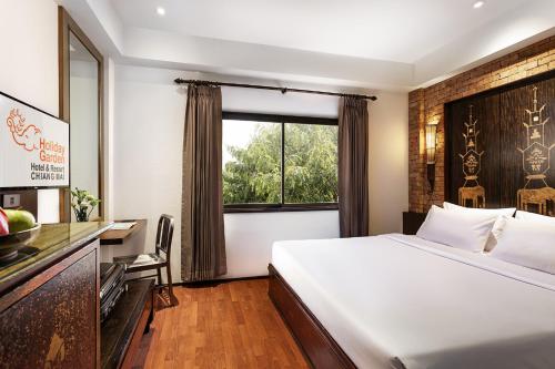 a hotel room with a bed and a window at Holiday Garden Hotel & Resort SHA EXTRA PLUS in Chiang Mai