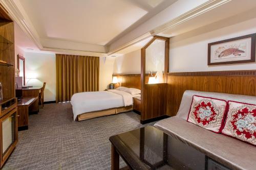um quarto de hotel com uma cama e um sofá em Kingshi Hotel Taipei em Taipei