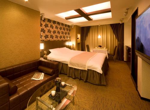 a hotel room with a bed and a couch at Carrot ISE (Adult Only) in Ise