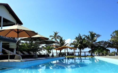 uma piscina no resort com guarda-sóis e palmeiras em IMAGINE Villa Hotel em Mirissa
