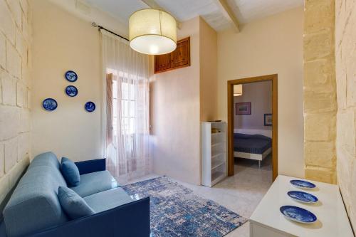 a living room with a blue couch and a table at Traditional Maltese Townhouse, Roof Terrace and Views in Senglea