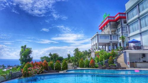a hotel with a swimming pool in front of a building at Hotel Santika Luwuk - Sulawesi Tengah in Luwuk
