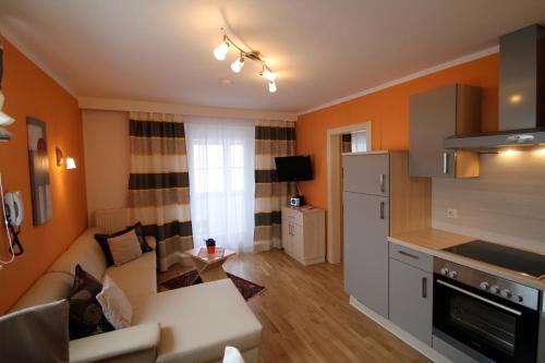 a living room with a couch and a kitchen at Seepension Neubacher KG in Nussdorf am Attersee