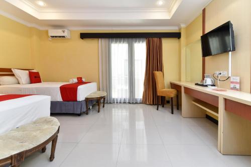 a hotel room with two beds and a desk at RedDoorz Plus near Mall Bali Galeria 2 in Denpasar