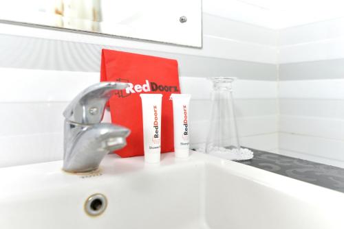 a sink with a faucet and two toothbrushes at RedDoorz Plus near Mall Bali Galeria 2 in Denpasar
