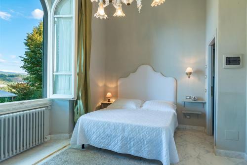 a bedroom with a white bed and a window at Relais Villa Al Vento in Incisa in Valdarno