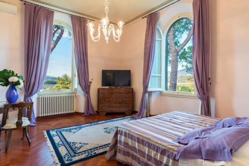 a bedroom with a bed and a tv and windows at Relais Villa Al Vento in Incisa in Valdarno