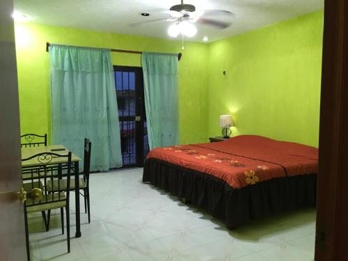 Apartamento Colonial Campeche في كامبيش: غرفة نوم بجدران خضراء وسرير وطاولة
