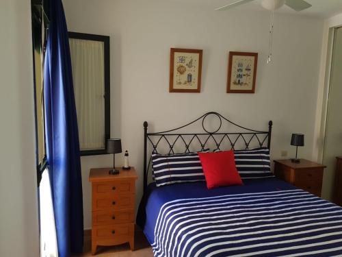 ein Schlafzimmer mit einem blauen und weißen Bett mit einem roten Kissen in der Unterkunft Apartamento el Atunito, Atlanterra in Zahara de los Atunes