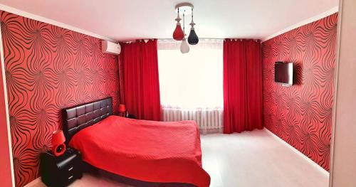 een rode slaapkamer met een bed met rode gordijnen en een raam bij Stylish apartment on street Ismail 84 in Chişinău