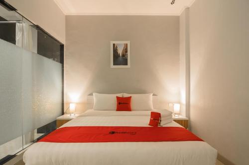 - une chambre avec un grand lit blanc et des oreillers rouges dans l'établissement RedDoorz Plus near Soekarno Hatta Airport 2, à Tangerang