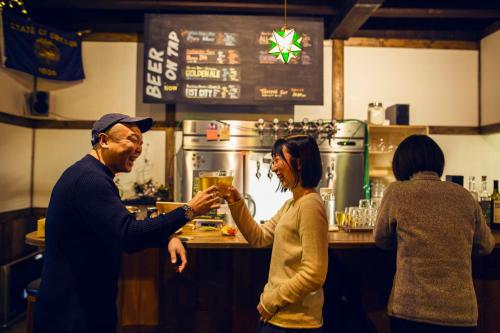 a man and a woman standing at a bar at Otaru Tap Room & Hostel in Otaru