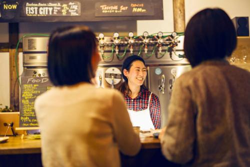 three women standing at a counter in a coffee shop at Otaru Tap Room & Hostel in Otaru