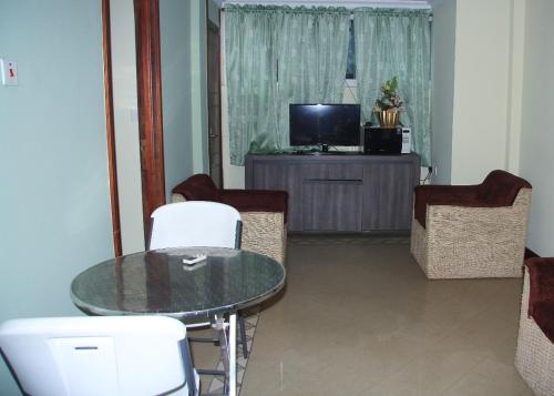 a living room with a table and chairs and a television at Ridge Over Suite in Accra