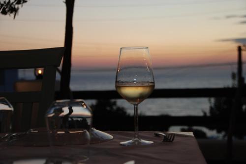 a glass of wine sitting on a table with the sunset at Saranda Hotel in Sarandë