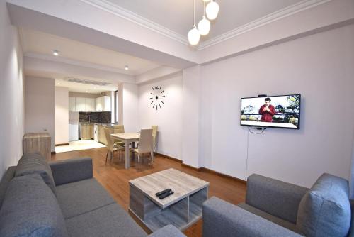 a living room with a couch and a tv on a wall at Luxury apartments just near Republic Square in Yerevan