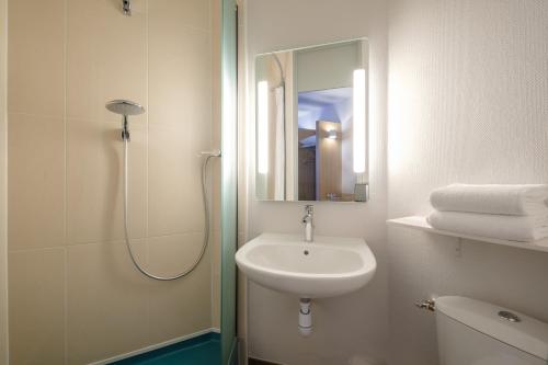a bathroom with a sink and a shower with a mirror at B&B HOTEL Calais Centre St Pierre in Calais