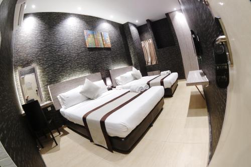two beds in a hotel room with a mirror at Here Hotel in Skudai