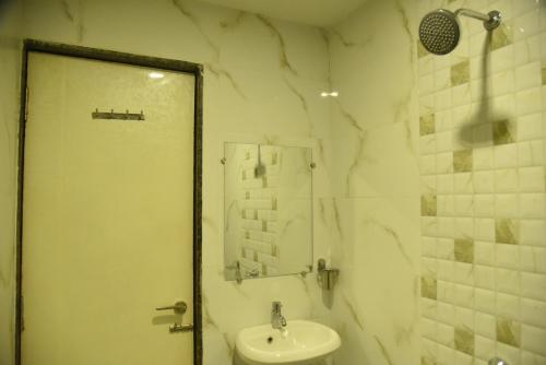 a white bathroom with a sink and a shower at Sai Vidisha Palace in Shirdi