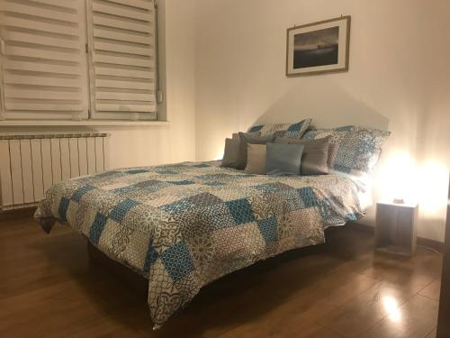 a bedroom with a bed with a quilt and a lamp at Apartment Galerija in Tuzla