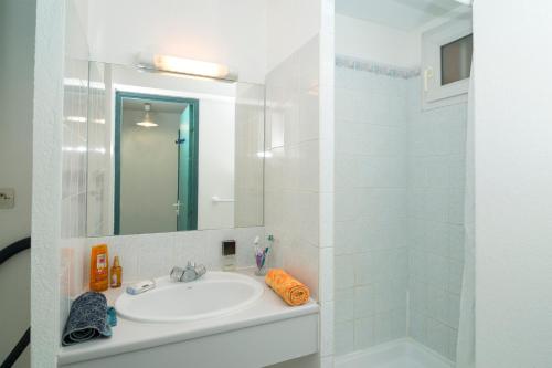 a white bathroom with a sink and a shower at Vacancéole - Savanna Beach- Terrasses de Savanna in Cap d'Agde