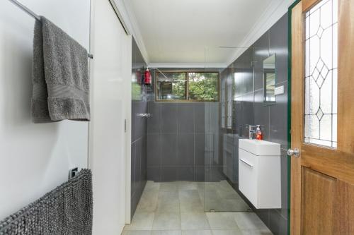 a bathroom with a shower with a toilet and a sink at Mena Creek Flower House in Mena Creek