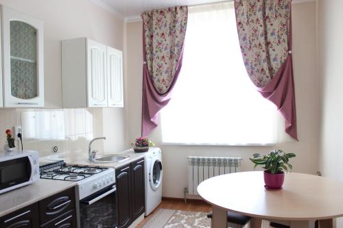 a kitchen with a stove and a table and a window at Апарт отель Welcome in Taldykorgan